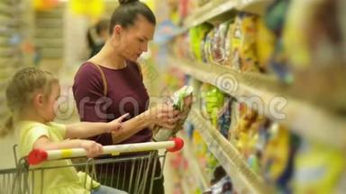 母亲和女儿在超市购物。 他们正在买早餐片。 一个女儿坐在超市